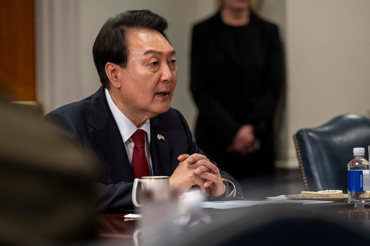 Korean President Yook Seok-yeol seated and speaking at a conference table