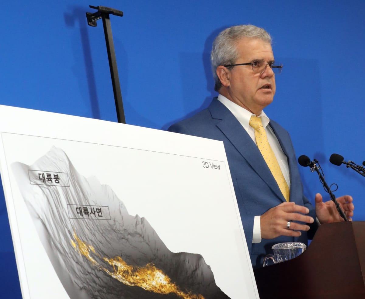 Vitor Abreu of geoscience research firm Act-Geo speaks at a lectern beside chart of finding of oil reserves in East Sea