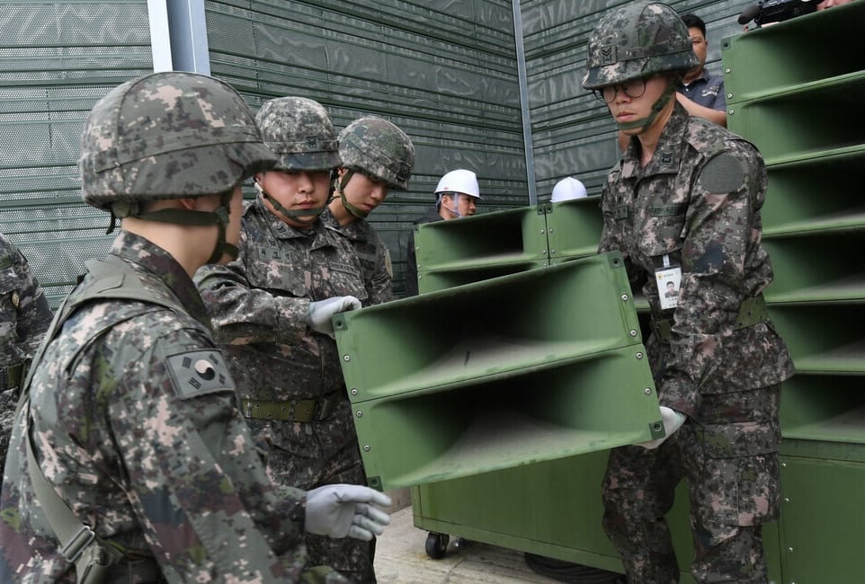 South Korean soldiers in fatigues holding an outdoor loudspeaker