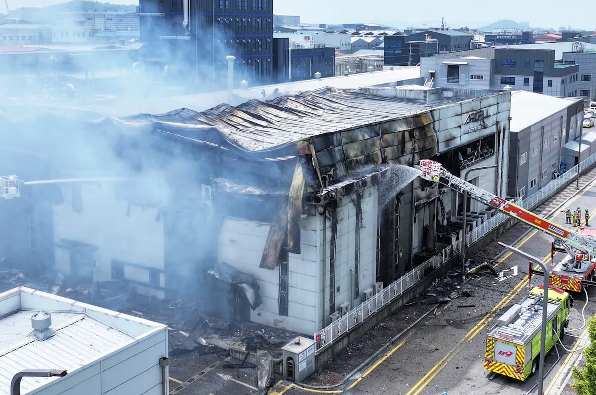 Fire-wrecked building smoldering with fire trucks spraying water