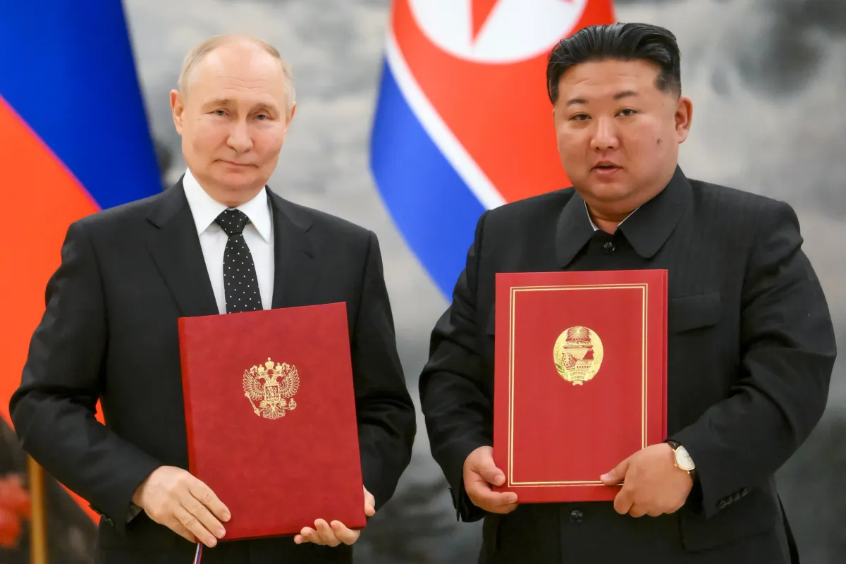 Vladimir Putin and Kim Jong Un display their agreement binders after the signing ceremony