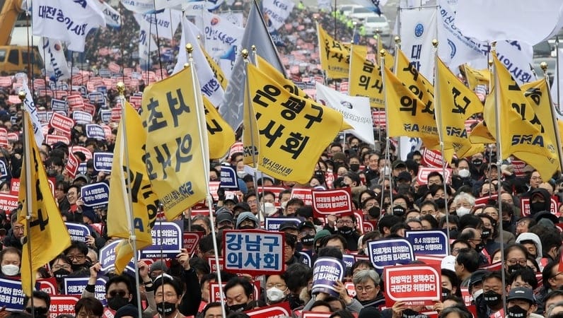 A large crowed of South Korean doctors protesting government medical policies with signs and flags